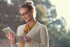 woman outdoors holding a tablet and smiling